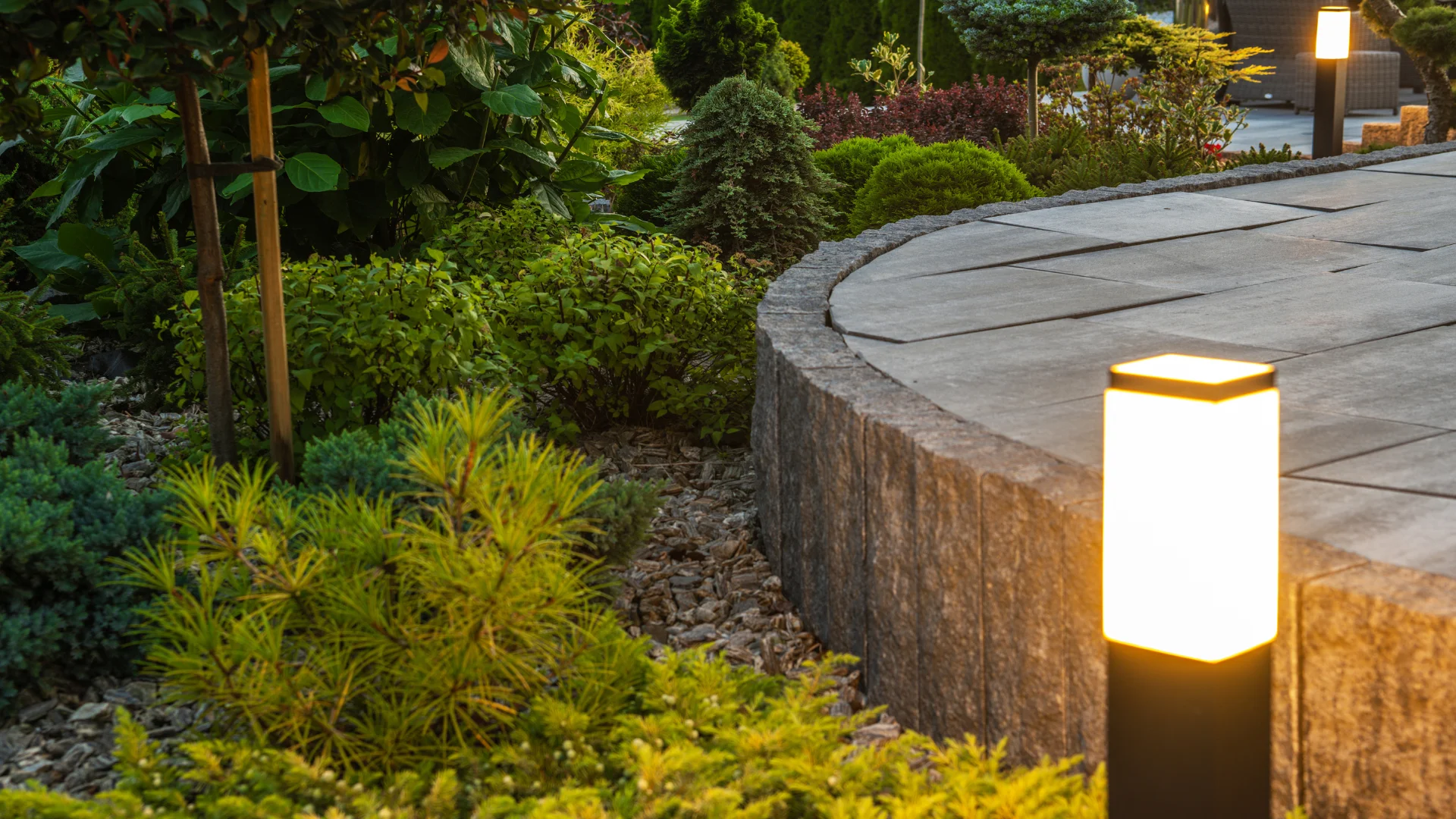 Low-voltage landscape lighting illuminating a North Texas patio and garden after sunset